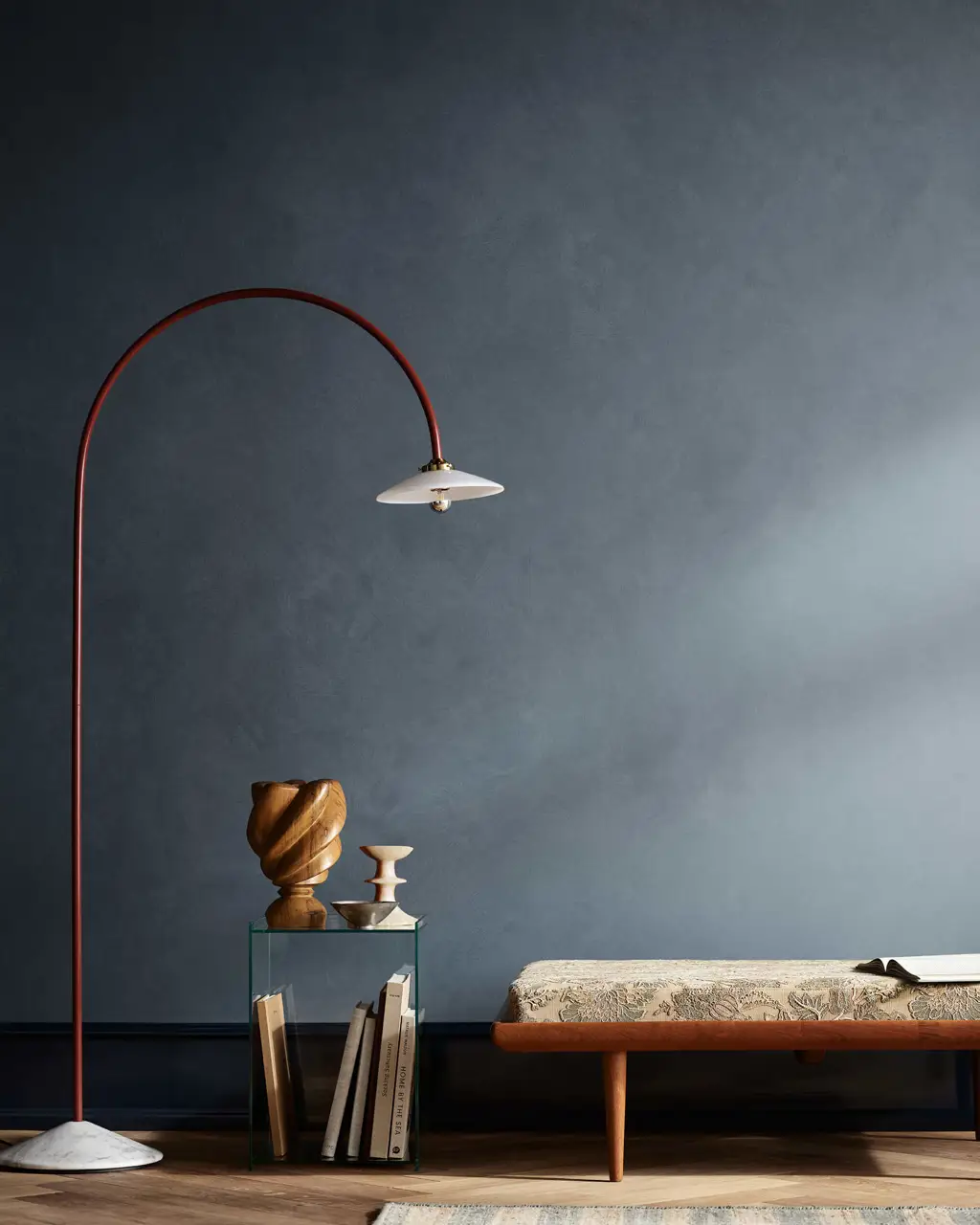 En stue med kalkmalte vegger i blå Jotun 4638 Byge, høy gulvlist i mørkeblå Jotun 4403 Midnight Blue, med en lampe, et sidebord og en benk