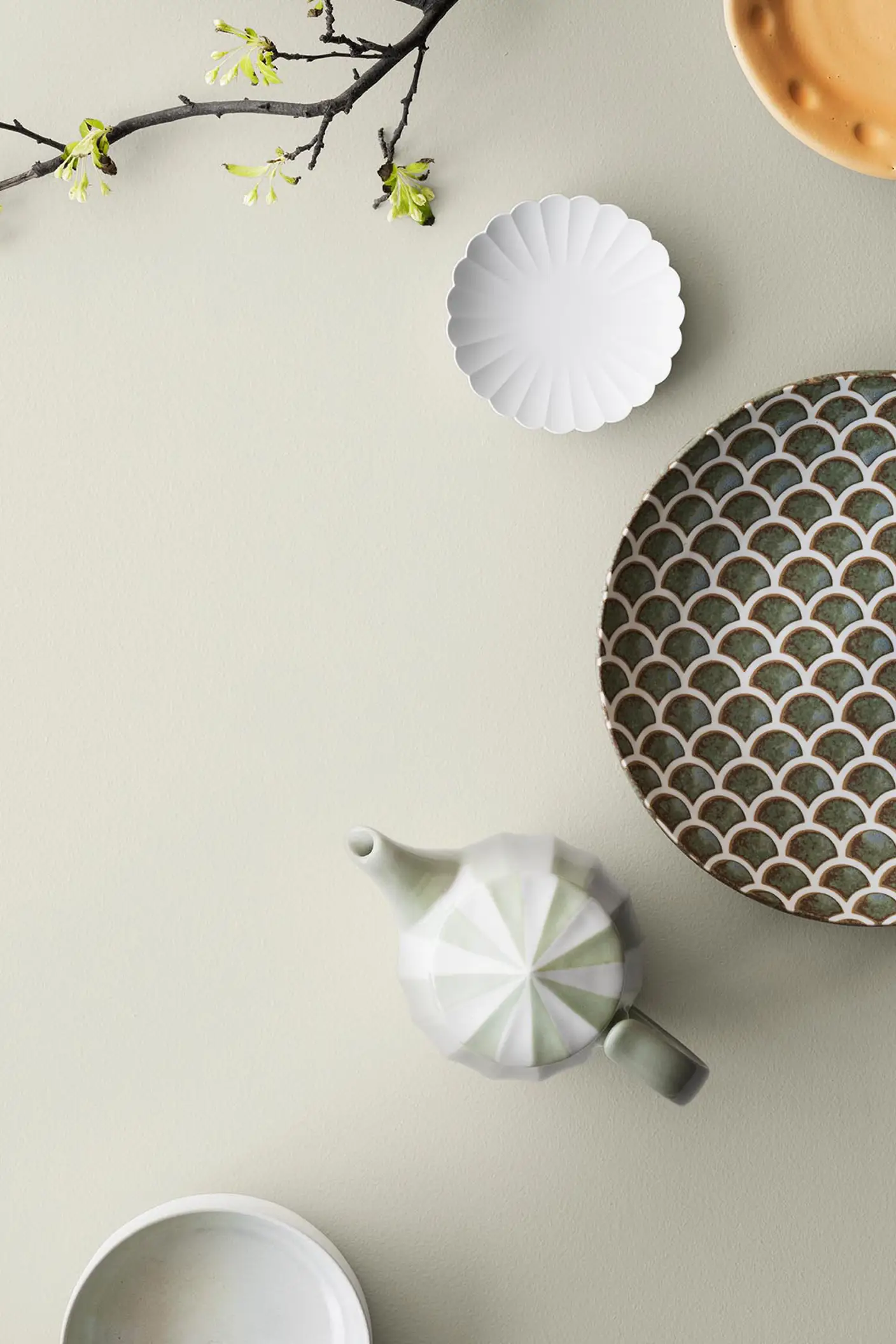 Dekorativt service og forårsgren på en varm, dæmpet baggrund malet med 10678 Space fra Jotun.