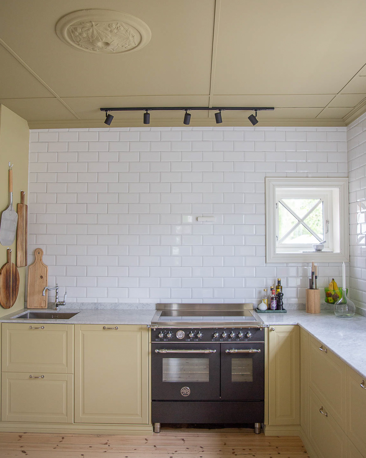 Kjøkken malt gult med Jotun Earthy Yellow, mørkere gult tak i Jotun Khaki Yellow, hvite metrofliser å vegg og marmorbenkeplate.