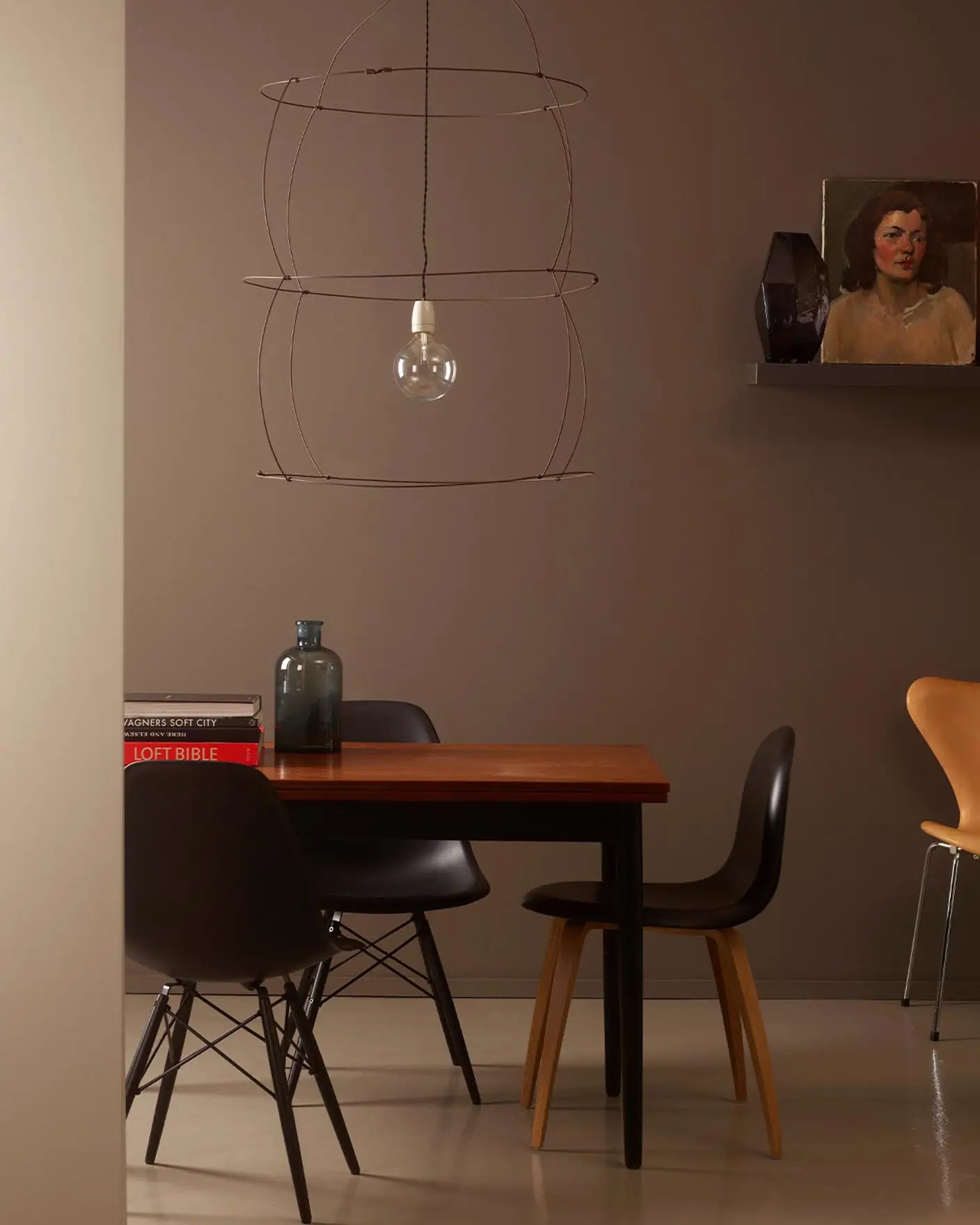 Ett stämningsfullt matrum med en dämpad brun vägg målad med Jotun 10249 Sober, mjukt ljus och noga utvalda konstverk och föremål. Accentväggen framför är målad med Jotun 0553 Ascott.