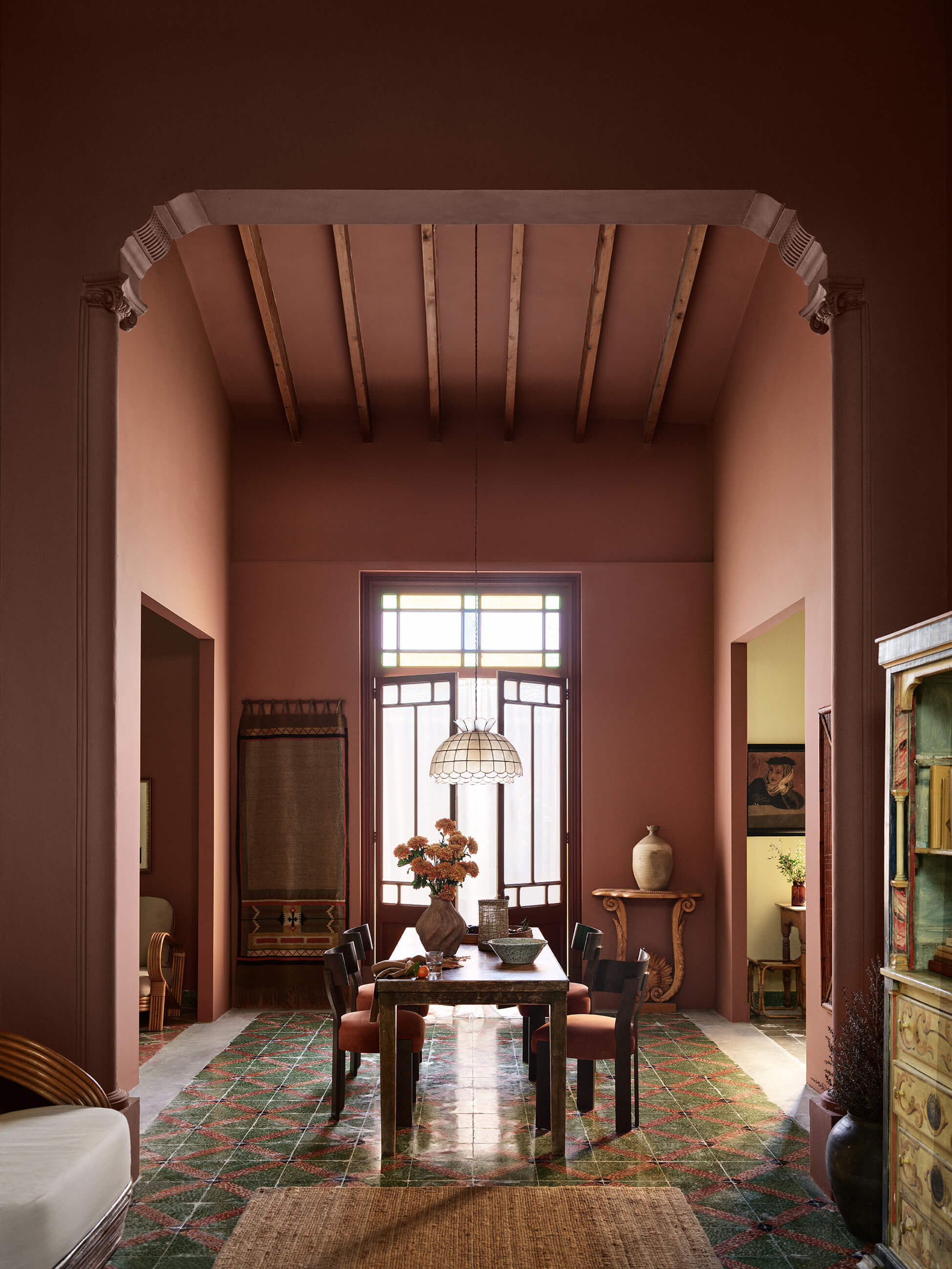 A kitchen dining space with high ceilings and tiled floors painted in Jotun 2993 Kilim, Jotun 20118 Amber Red, and Jotun 1627 Retro