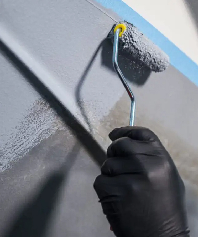 Hånd med sort hanske holder malingsrulle og påfører grunning av båt med produkter fra Jotun