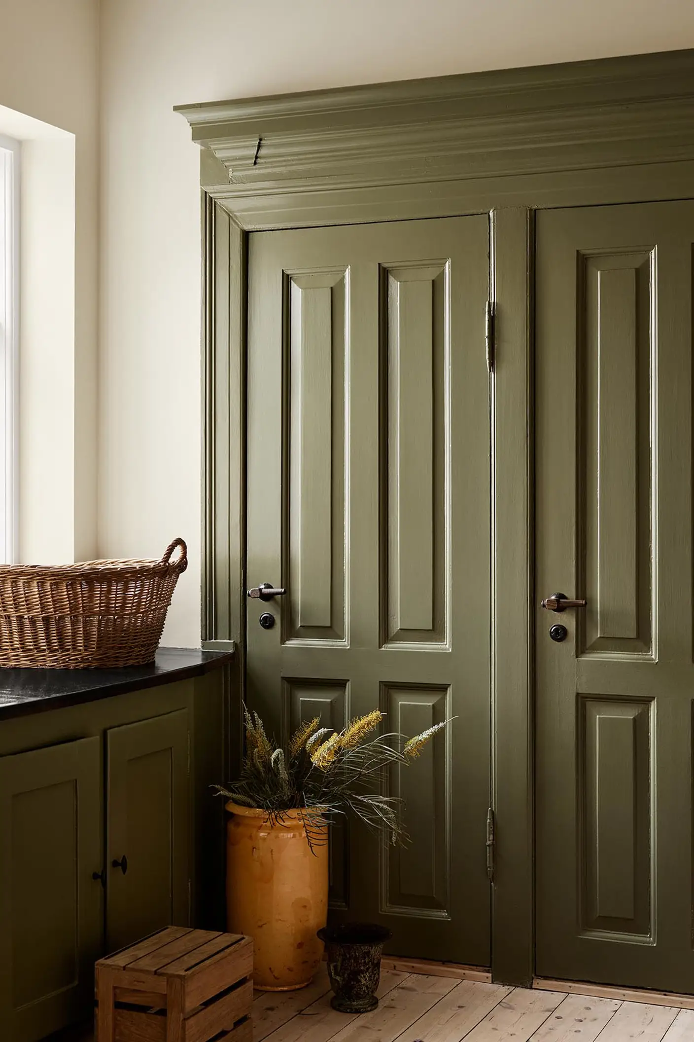 Kitchen with olive-green cabinets in the colour 8597 Seaweed Green against a muted yellow wall painted with 12079 Gleam from Jotun.