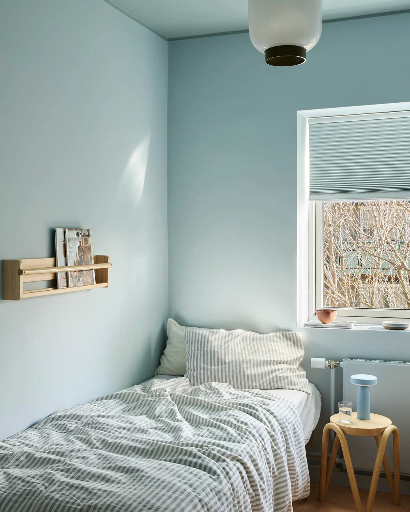 Soverommet er malt i Jotun 6167 Spring Breeze, med taket i 6236 Darjeeling; minimalistisk innredning med en krakk i lyst tre og stripete sengetøy.