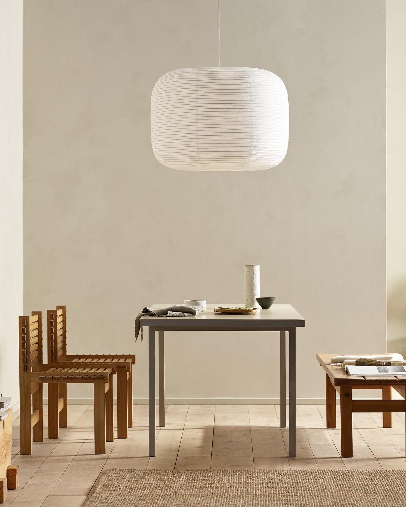 Minimalist dining area with wooden chairs, pendant light, and golden beige walls painted with the colour 12308 Unbleached from Jotun.