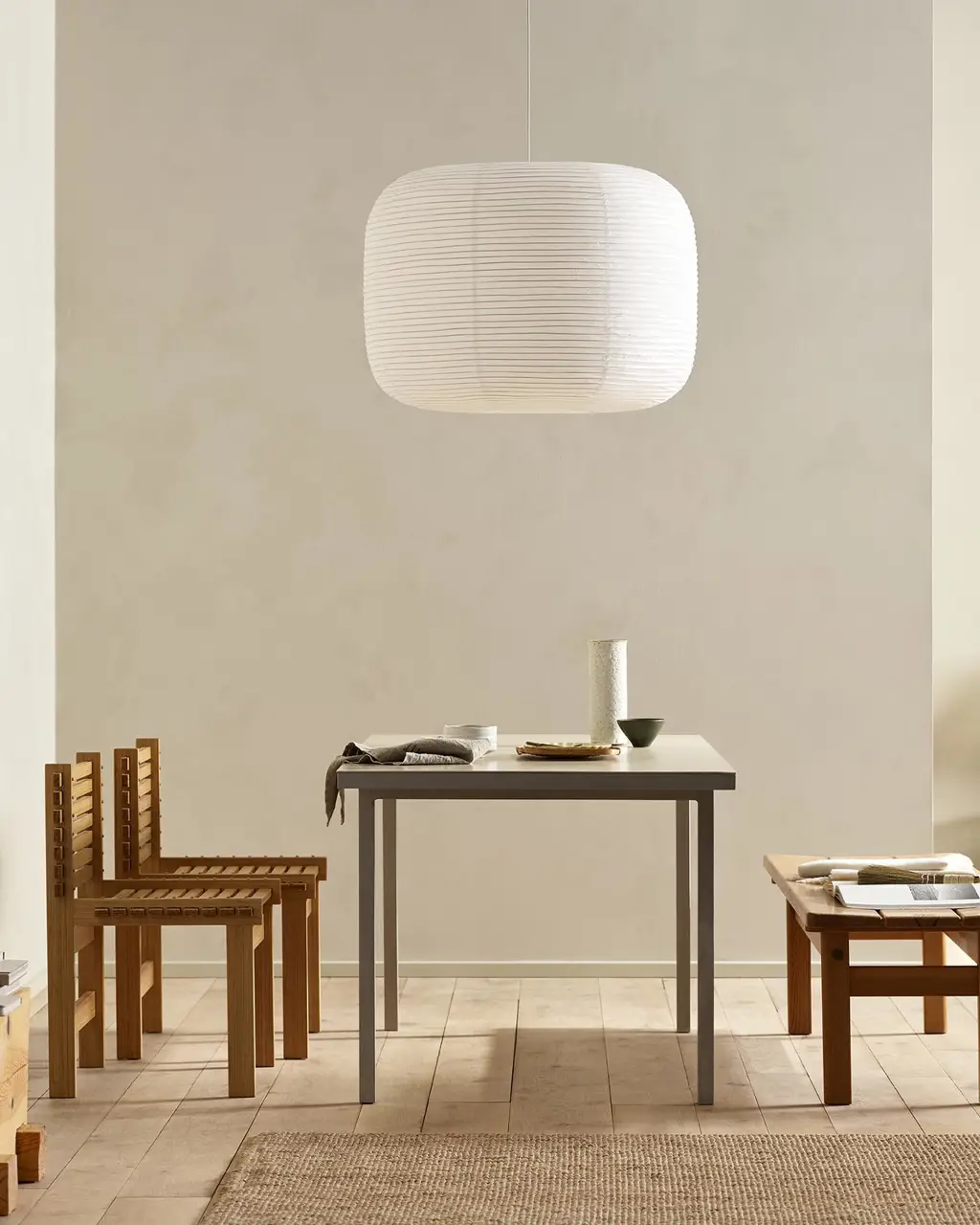 Minimalist dining area with wooden chairs, pendant light, and golden beige walls painted with the colour 12308 Unbleached from Jotun.