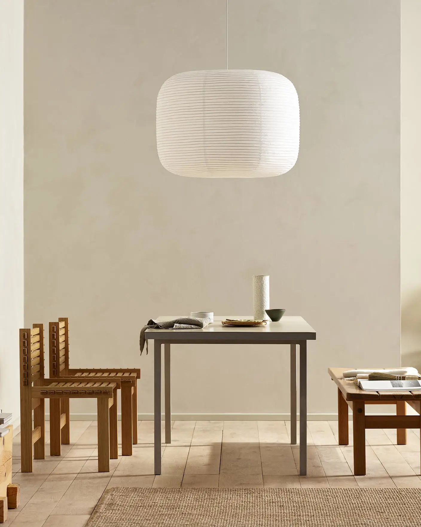 Minimalist dining area with wooden chairs, pendant light, and golden beige walls painted with the colour 12308 Unbleached from Jotun.