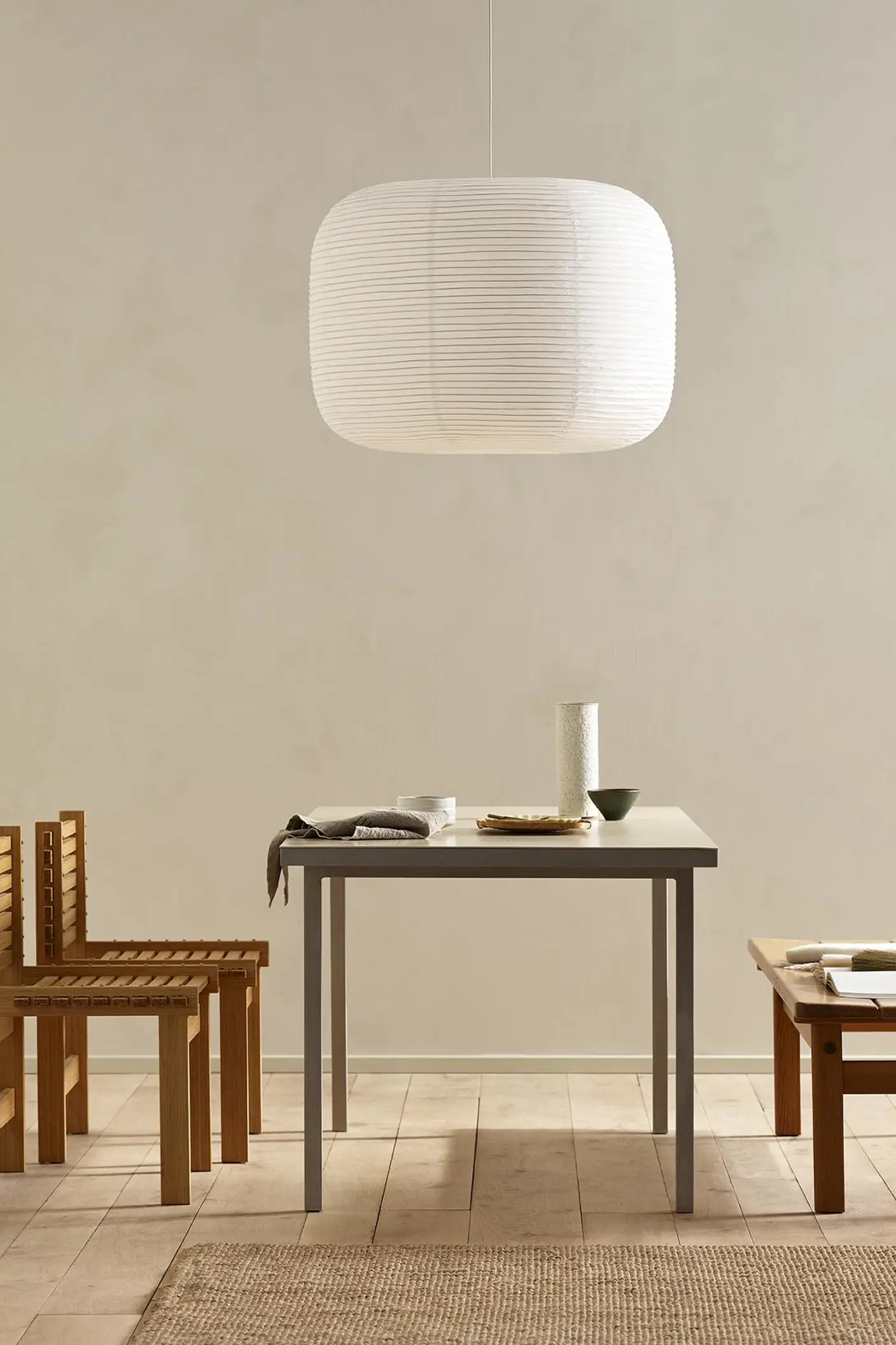 Minimalist dining area with wooden chairs, pendant light, and golden beige walls painted with the colour 12308 Unbleached from Jotun.