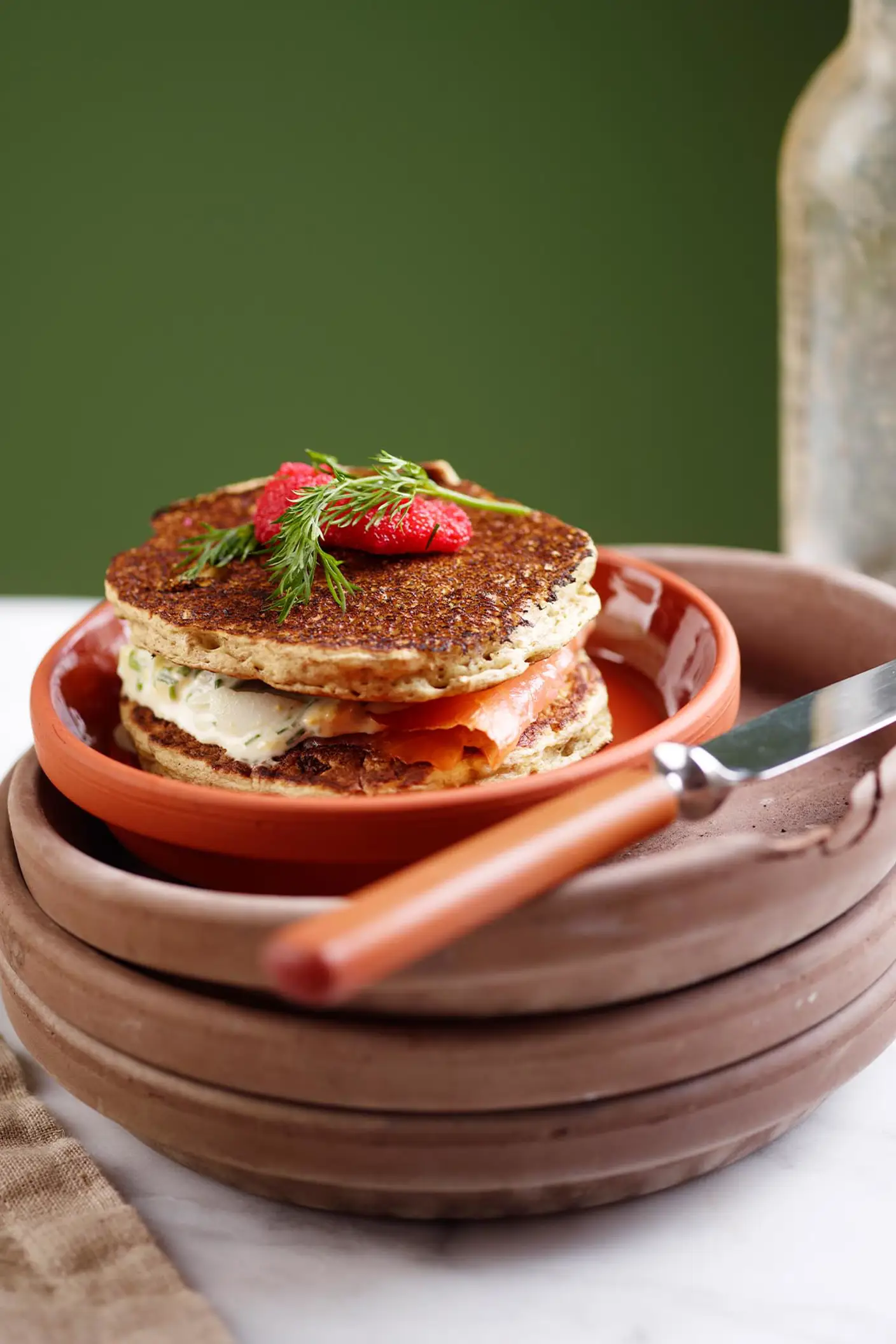 Una pila de panqueques en cerámica rústica sobre un fondo verde amarillento intenso pintado con Jotun 0125 Palm Leaf.