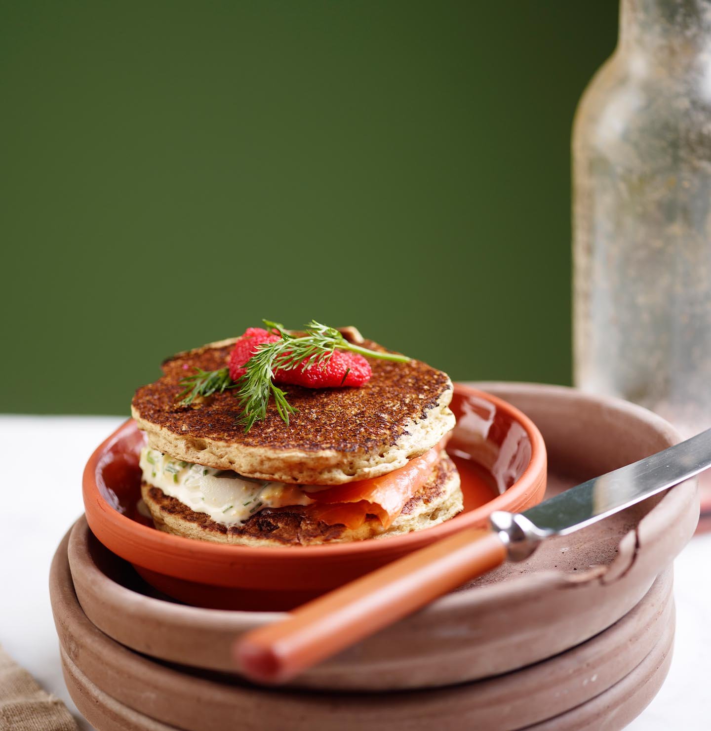 Stabel med pannekaker i rustikt steingods mot en dyp gulgrønn bakgrunn malt med Jotun 0125 Palmetto.