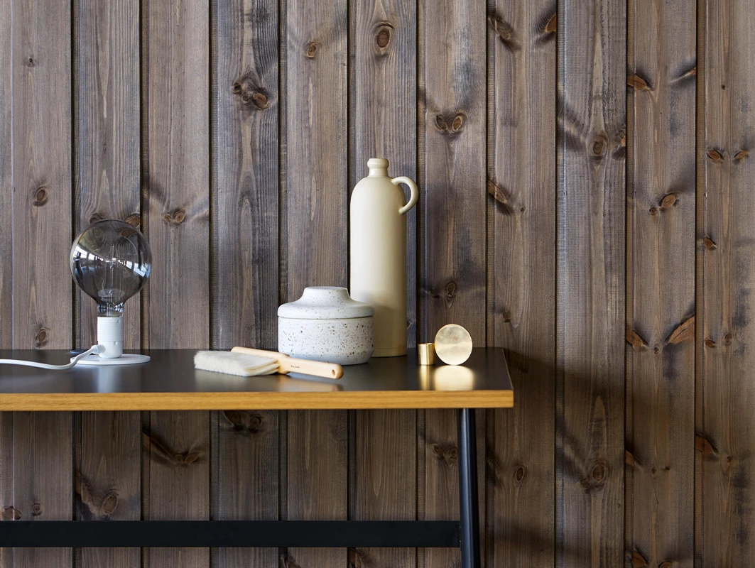 Mørk brunbeiset trepanel på vegg beiset med interiørbeis fra Jotun, lun skandinavisk stil, dempet stemningslys, interiørbeis