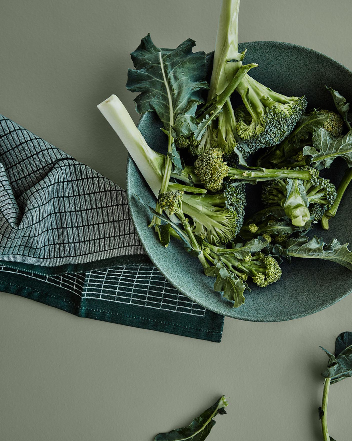 Färsk broccoli i en grön keramikskål står på en dämpad grön yta målad med färgen 7628 Treasure från Jotun, för en lugn och jordnära känsla i köket.