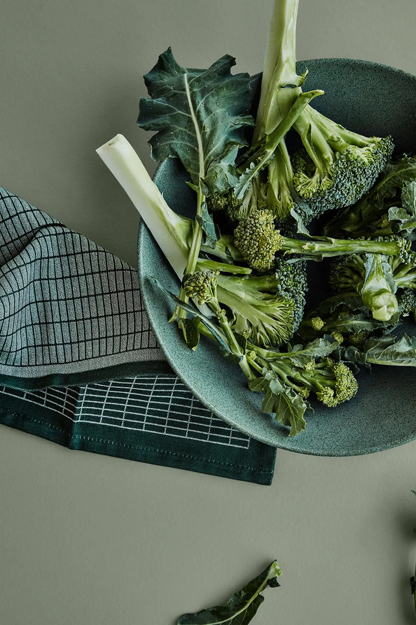 Färsk broccoli i en grön keramikskål står på en dämpad grön yta målad med färgen 7628 Treasure från Jotun, för en lugn och jordnära känsla i köket.