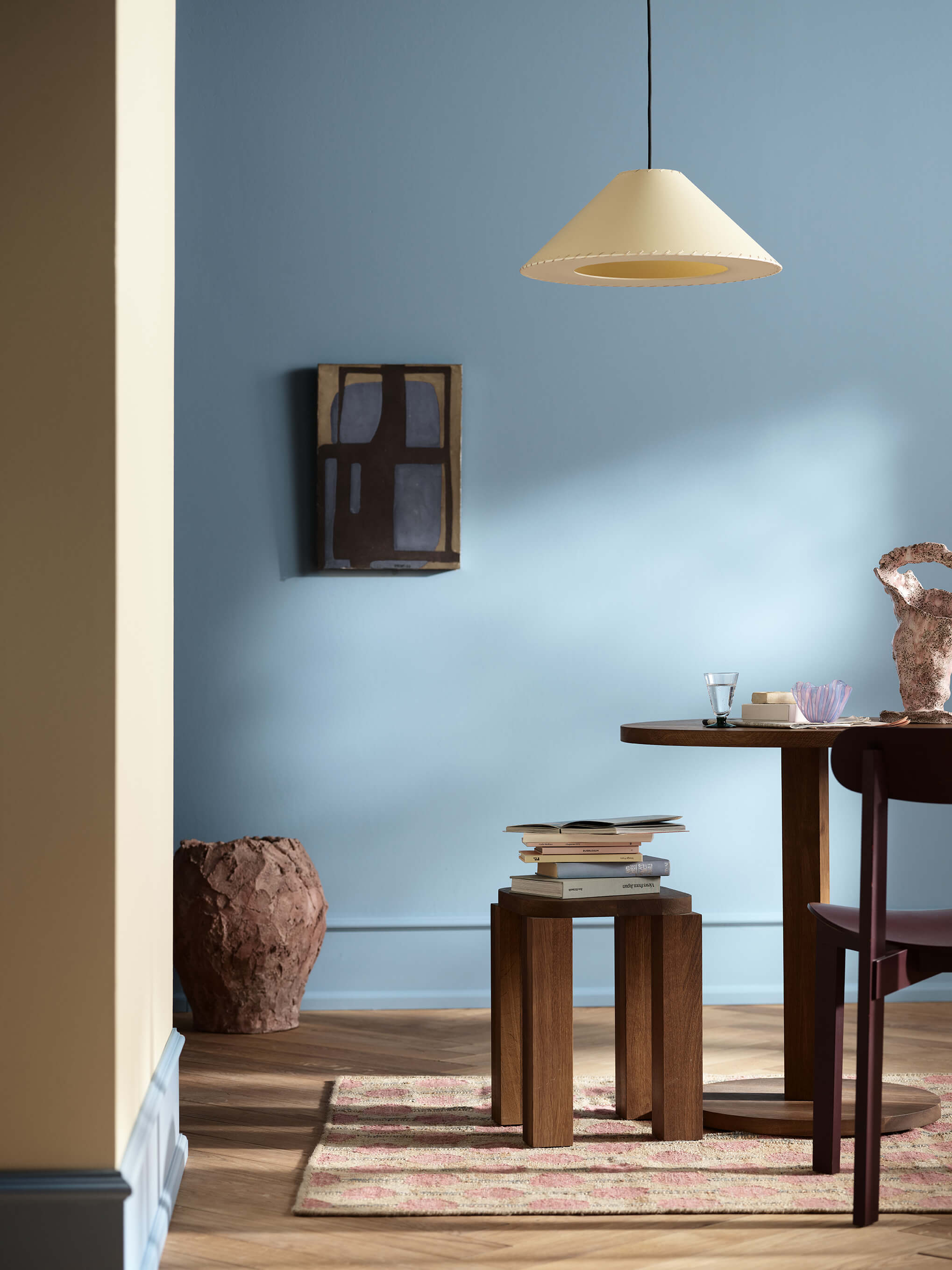 Spiseplass med blå bakvegger i fargen Jotun 4223 Sama og vegg i forgrunnen i den beige fargen Jotun 11365 Morning Glow. Spiseplassen har pendellampe, bord og krakk