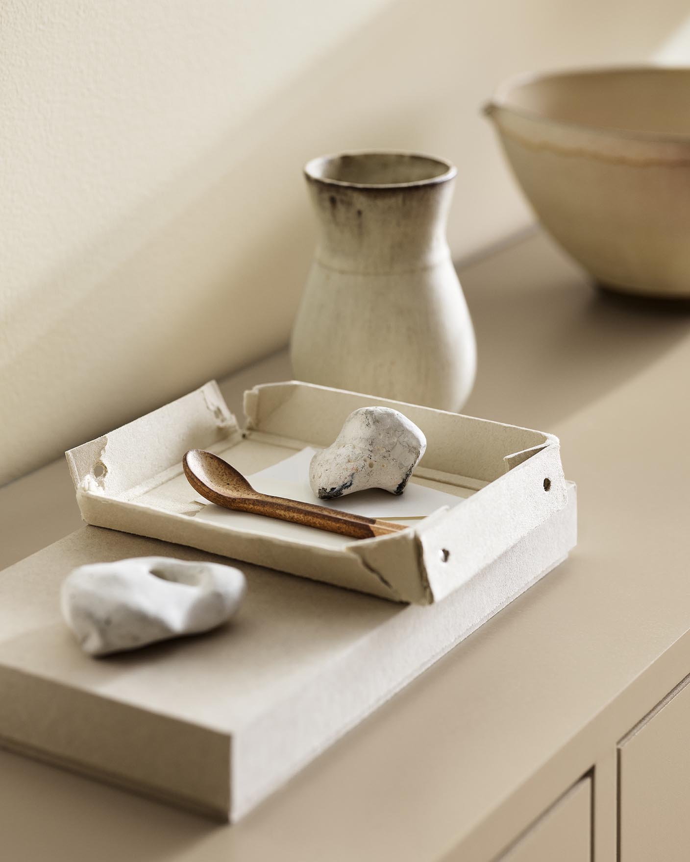 A ceramic vase, tray, and white stones against a wall painted with the colour 1625 Soul from Jotun.