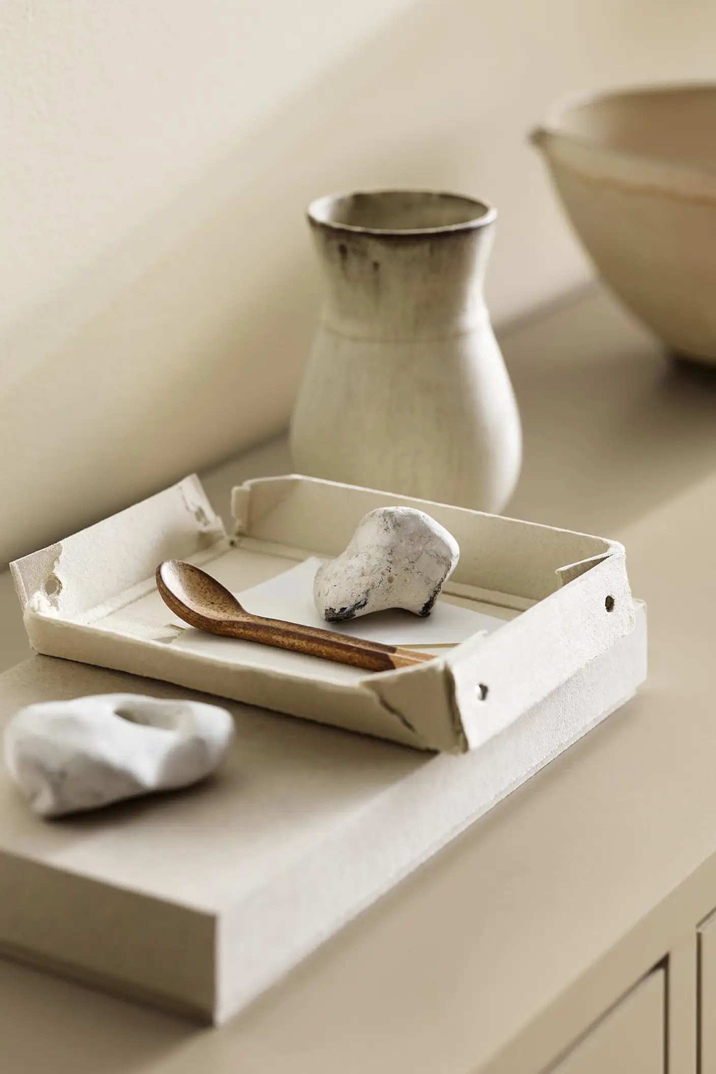 A ceramic vase, tray, and white stones against a wall painted with the colour 1625 Soul from Jotun.
