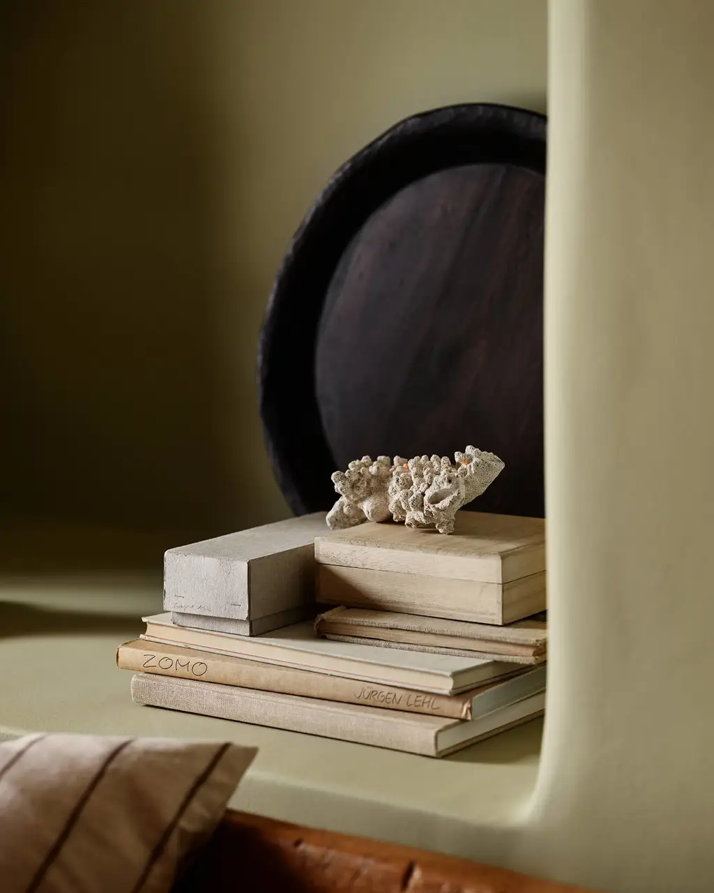 A stack of books and decorative objects on a bedroom shelf painted in Jotun 0290 Biri