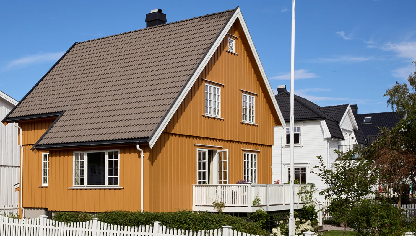 Klassisk villa med saltak, småsprossede vinduer og åpen terrassedør, fasade malt i dypt okergule JOTUN 0152 Staverngul og detaljer i hvit JOTUN 1001 Egghvit.
