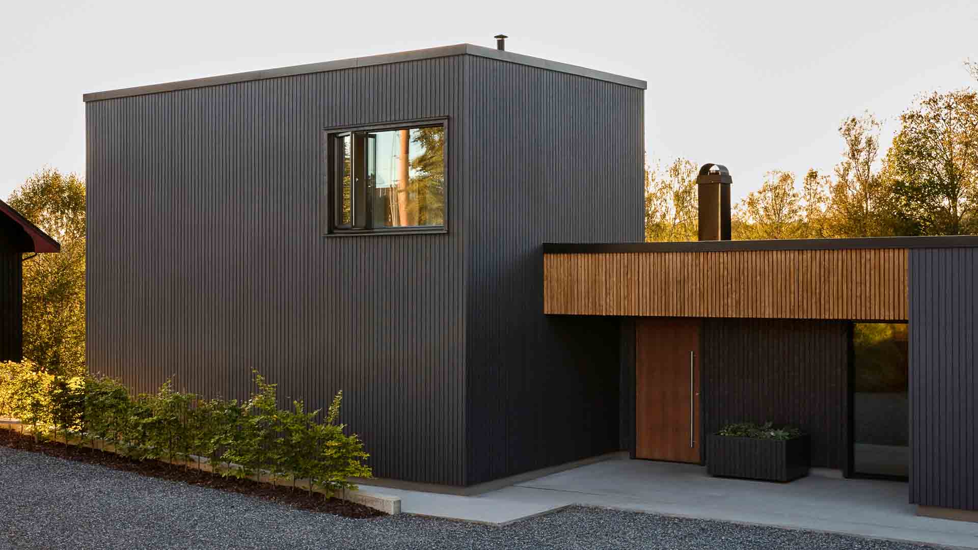 Moderne funkishus i matt sort malt med Jotun DRYGOLIN og treverk oljet med TREBITT WoodCare vedlikeholdsolje i varm brun.