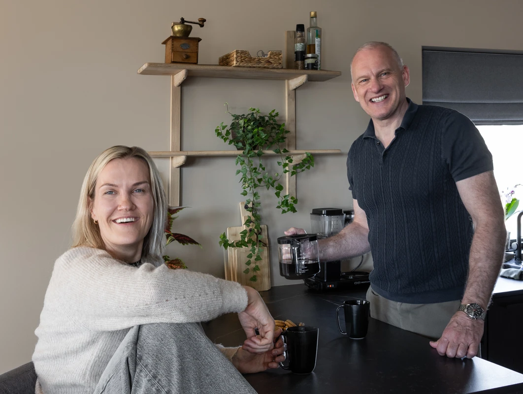 Lise Løke og Arne Senstad på sitt sorte kjøkken med varmt beigebrune vegger malt i Jotun Impression