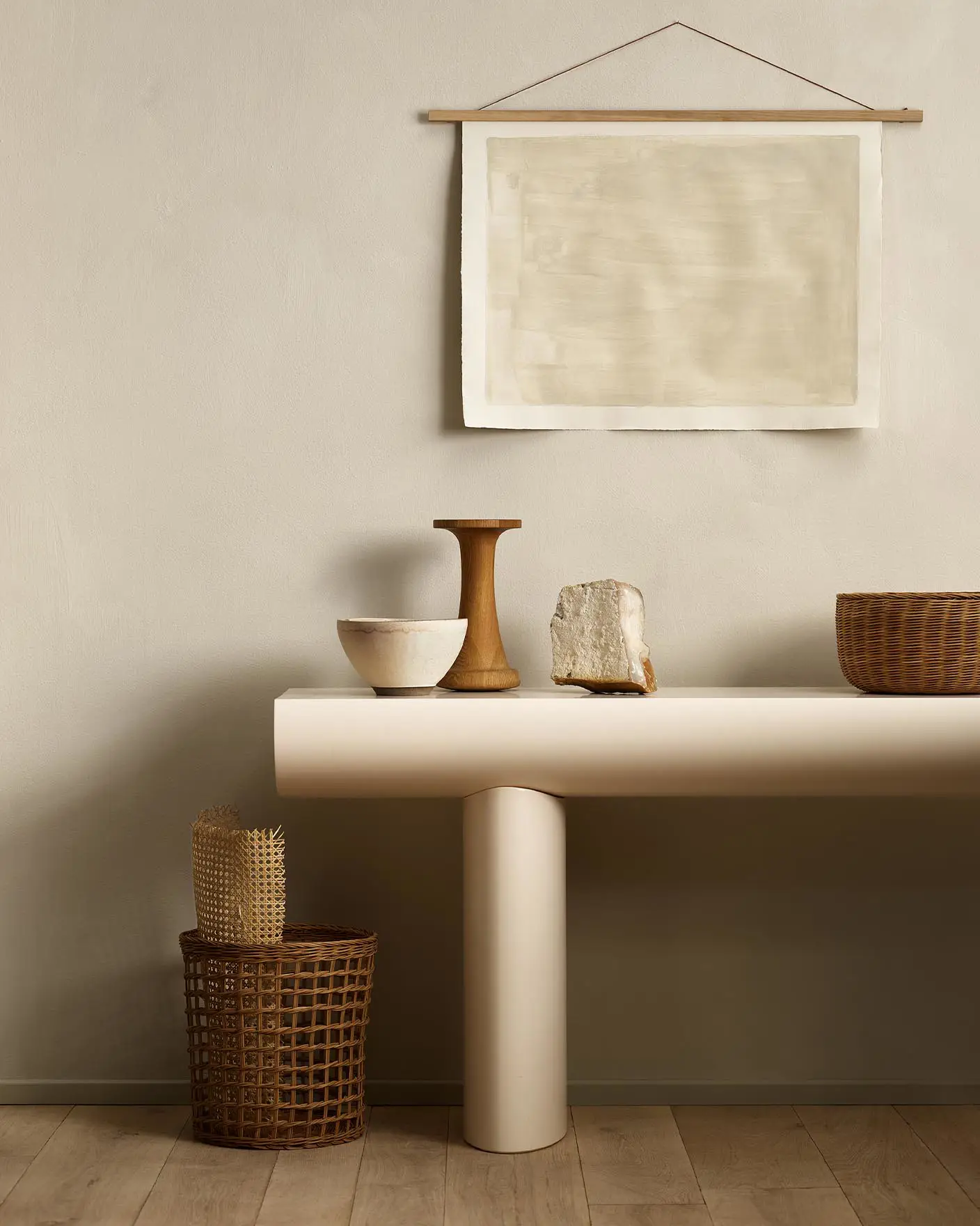 Minimalist console table with decor and baskets against a golden beige wall painted with Jotun's colour 12308 Unbleached.