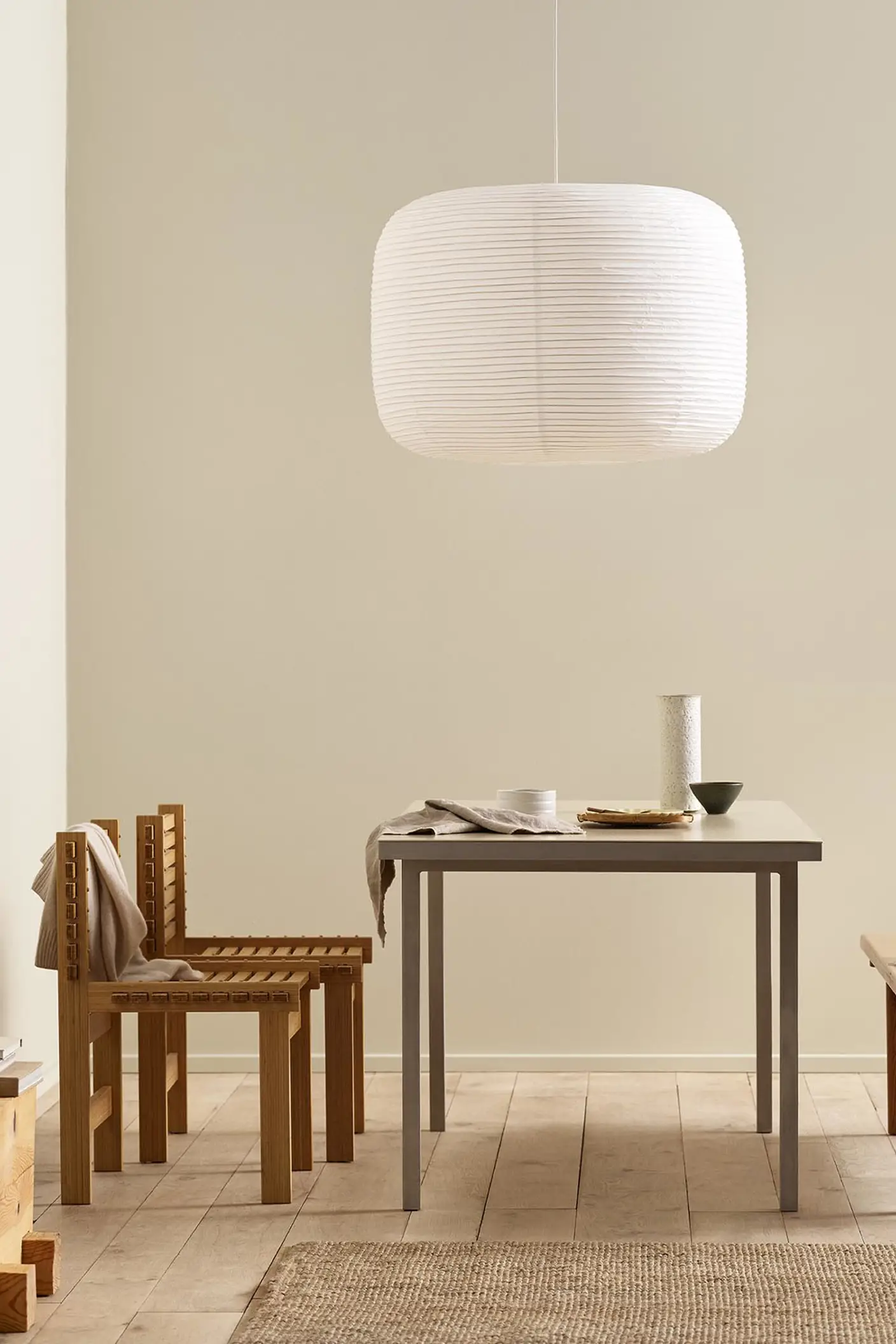 Minimalist dining area with wooden chairs, pendant light, and golden beige walls painted with the colour 12308 Unbleached from Jotun.