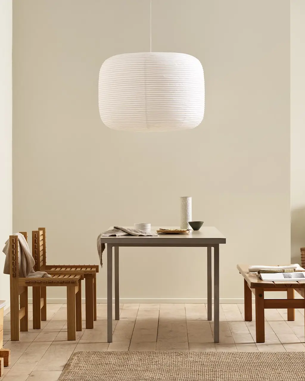 Minimalist dining area with wooden chairs, pendant light, and golden beige walls painted with the colour 12308 Unbleached from Jotun.