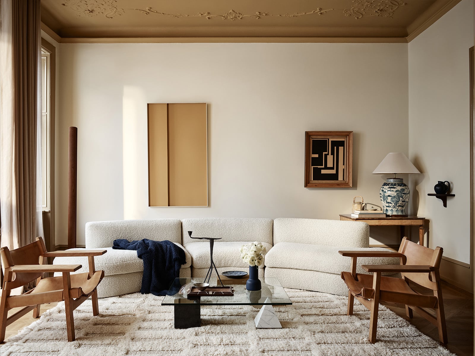 Elegant stue med kremfarget sofa, lenestoler i tre, glassbord og klassisk interiørdesign