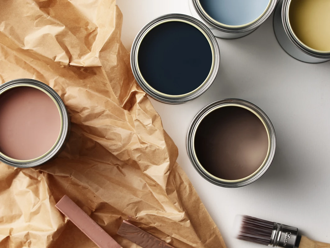 Fem åpne bokser maling sett ovenfra som viser fargene Jotun Balmy Pink, Midnight Blue, Sama, Retro og Mellow mot en ensfarget hvit bakgrunn.