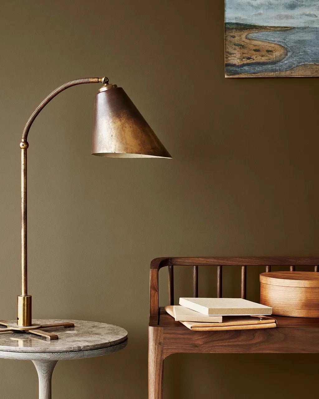 Brass lamp on a marble table next to a wooden bench, set against a golden brown wall painted with Jotun 10963 Golden Bronze.