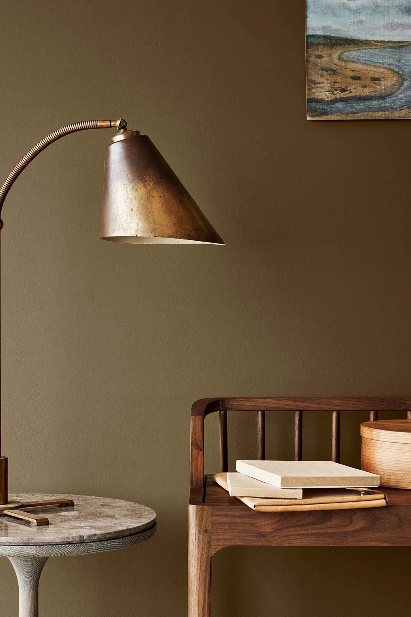 Messinglampe på et marmorbord ved siden af en trebenk, mod en gyldenbrun væg malet med Jotun 10963 Golden Bronze.