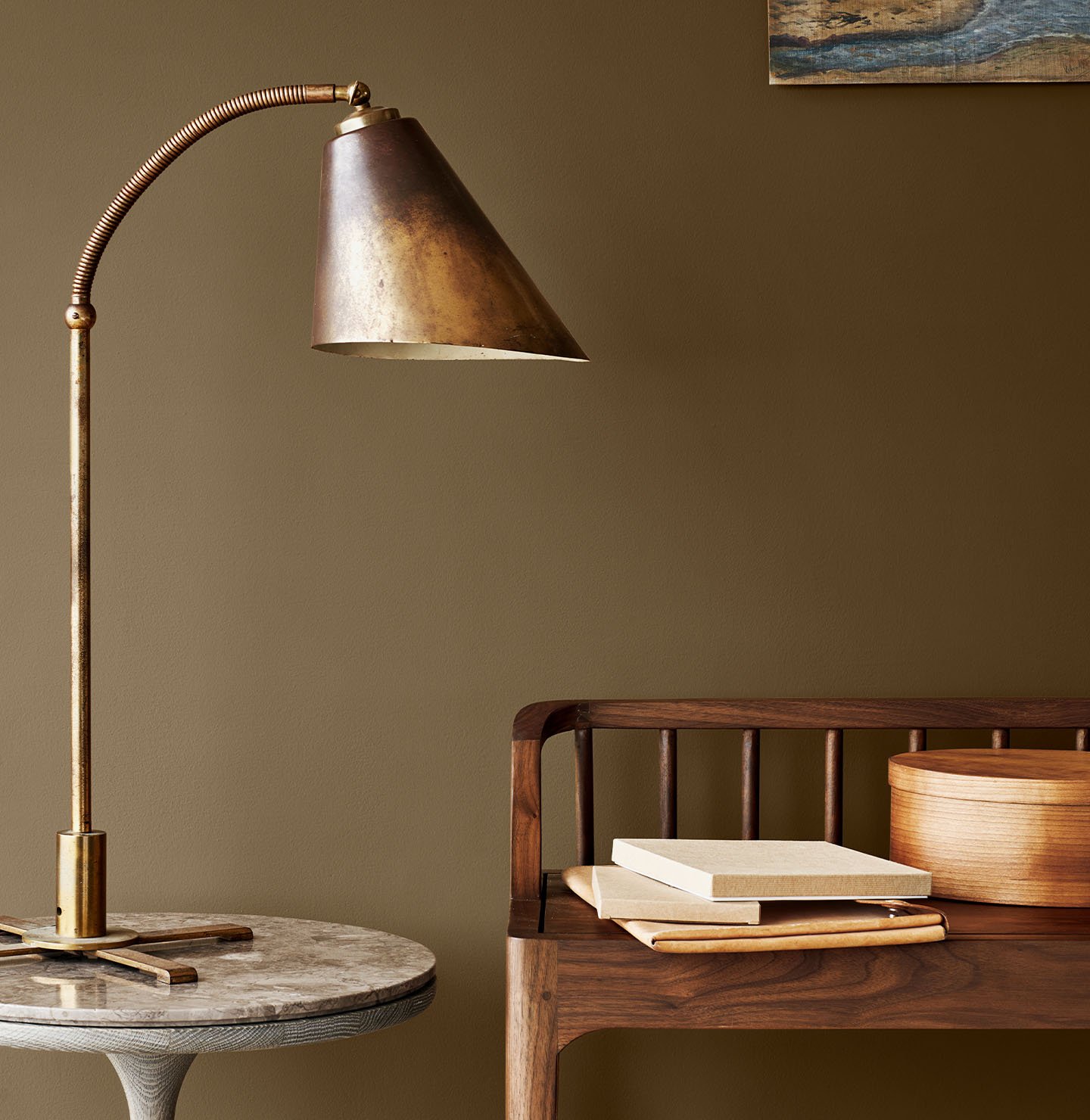 Messinglampe på et marmorbord ved siden av en trebenk, mot en gyldenbrun vegg malt med Jotun 10963 Golden Bronze.