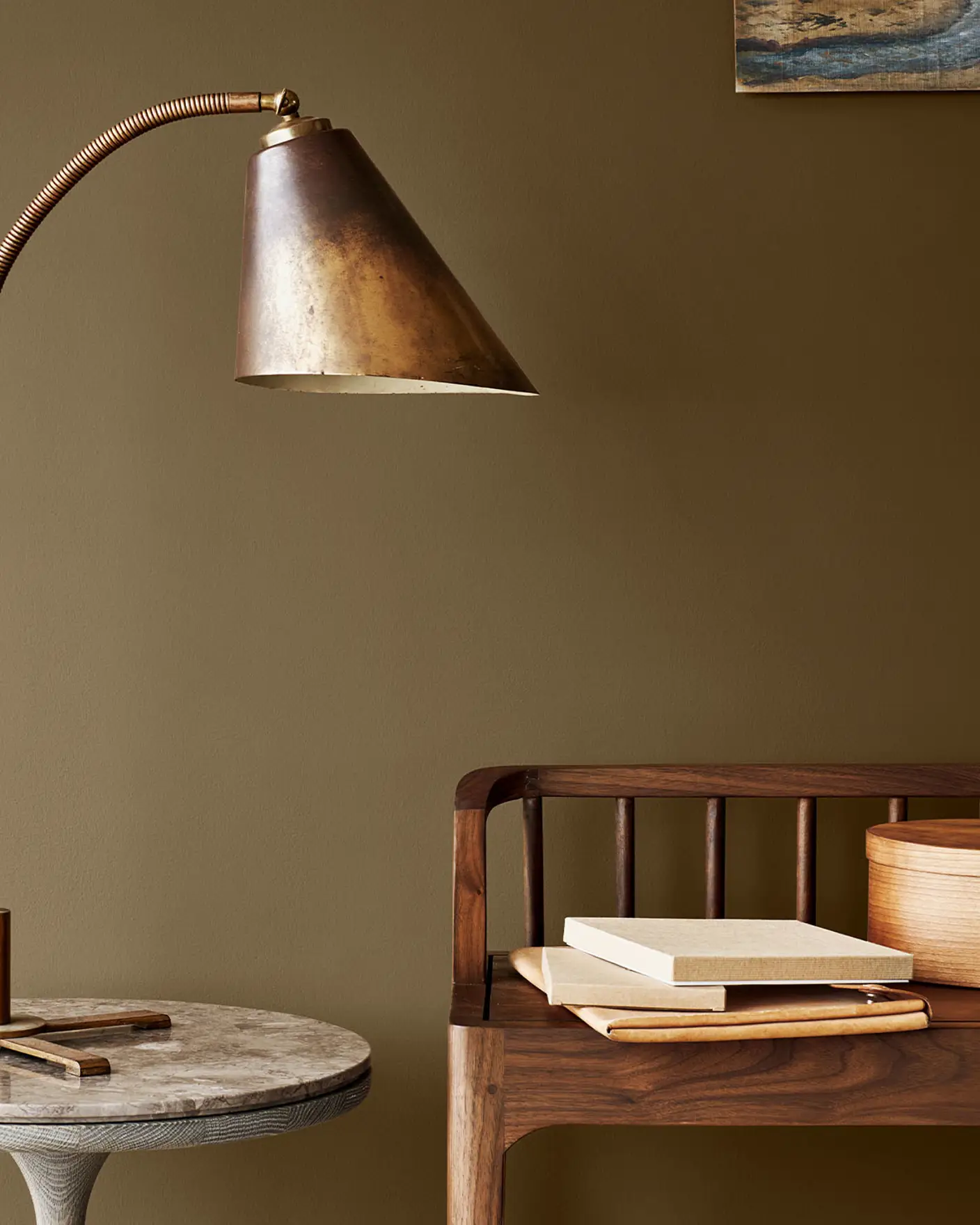 Messinglampe på et marmorbord ved siden av en trebenk, mot en gyldenbrun vegg malt med Jotun 10963 Golden Bronze.