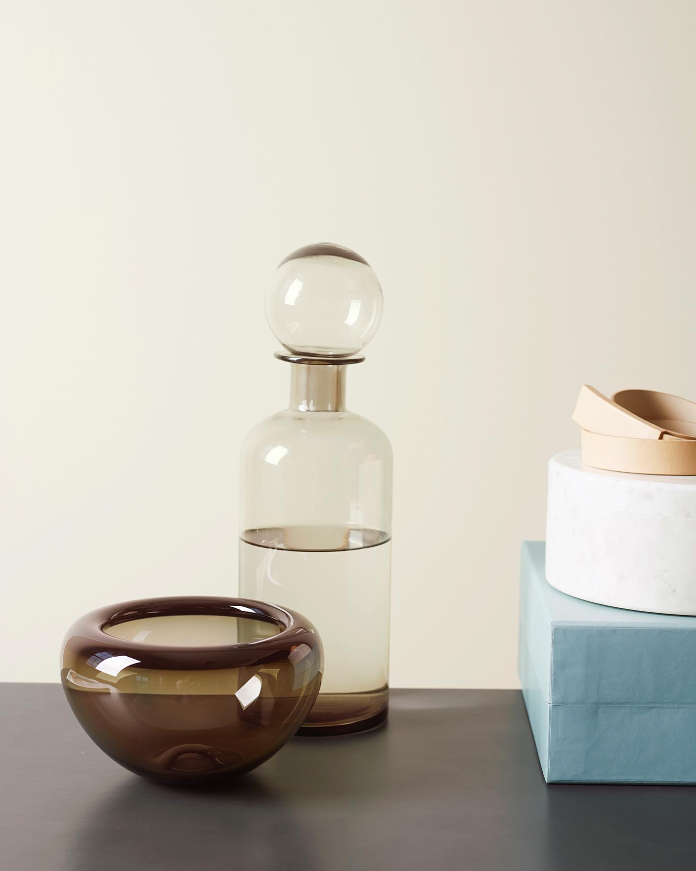 Minimalistisk styling med mjuka, gråtonade väggar målade med Jotun 1928 Sommarsnö och skulpturala glas- och keramikdetaljer i varma och kalla neutrala toner.