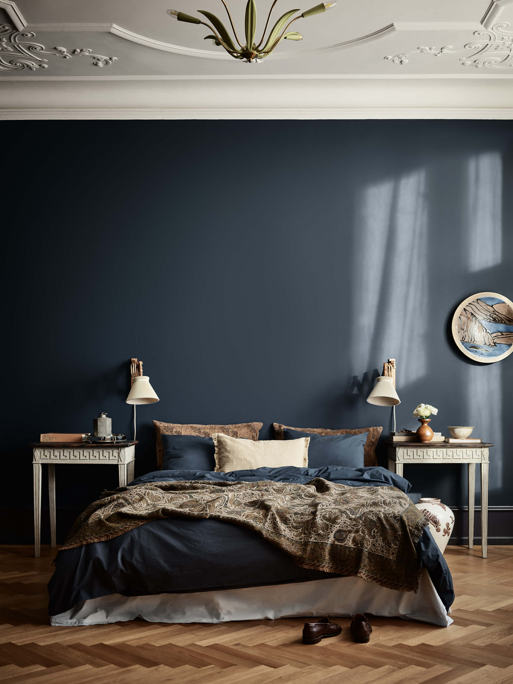 Et dramatisk soverom med vegger i dyp marineblått i Jotun 4403 Midnight Blue, et hvitt dekorativt tak i Jotun 11364 Century White og symmetriske nattbord