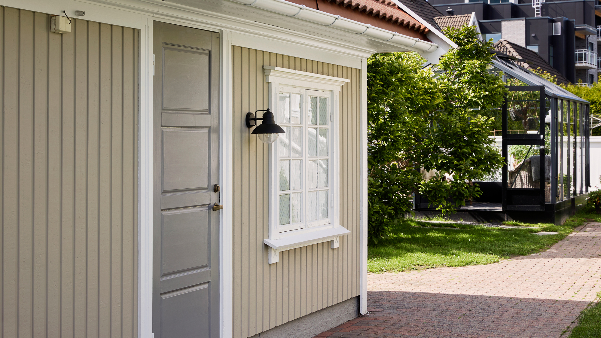 Beige yttervegger på garasje i Jotun Sandbeige med grå inngangsdør i Jotun Steel Grey