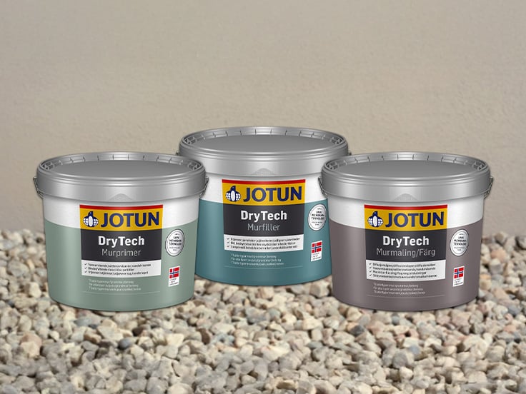 Tre spann med Jotun DryTech murmaling, murprimer og murfiller foran en malt grunnmur