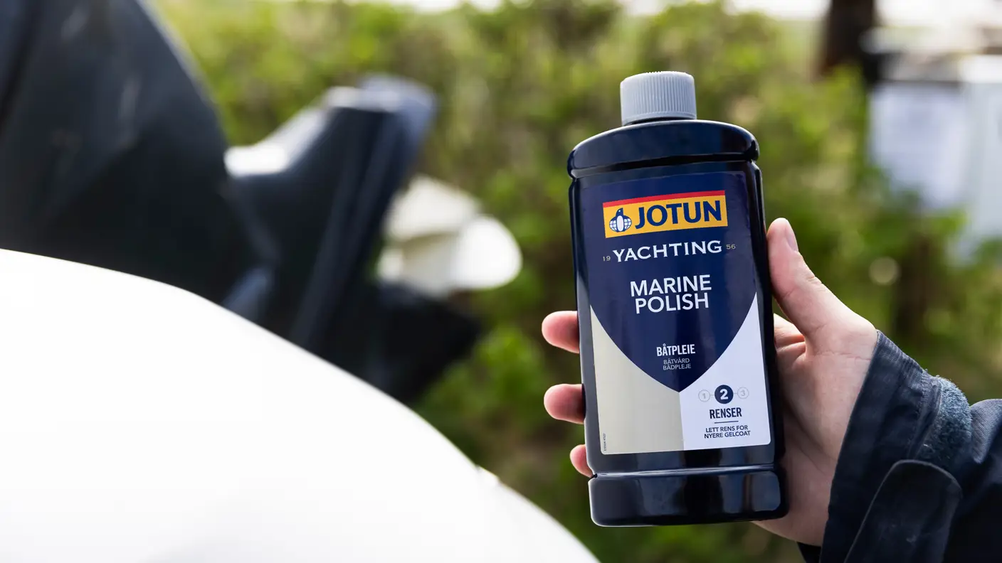 Flaske med Jotun Marine Polish holdes mot en båt