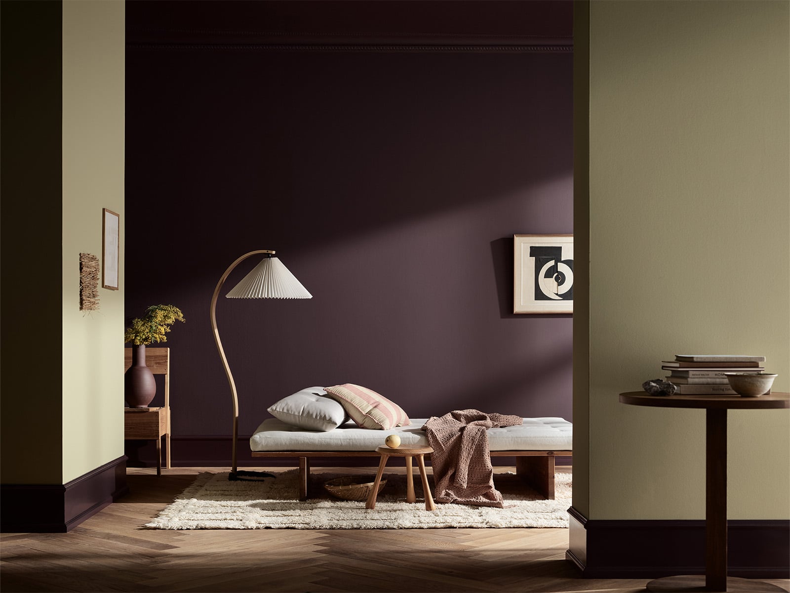Stilfullt soverom med mørk lilla vegg i fargen Jotun Velvet Plum malt med LADY Pure Color, enkel seng, gulvlampe, småbord og moderne interiør