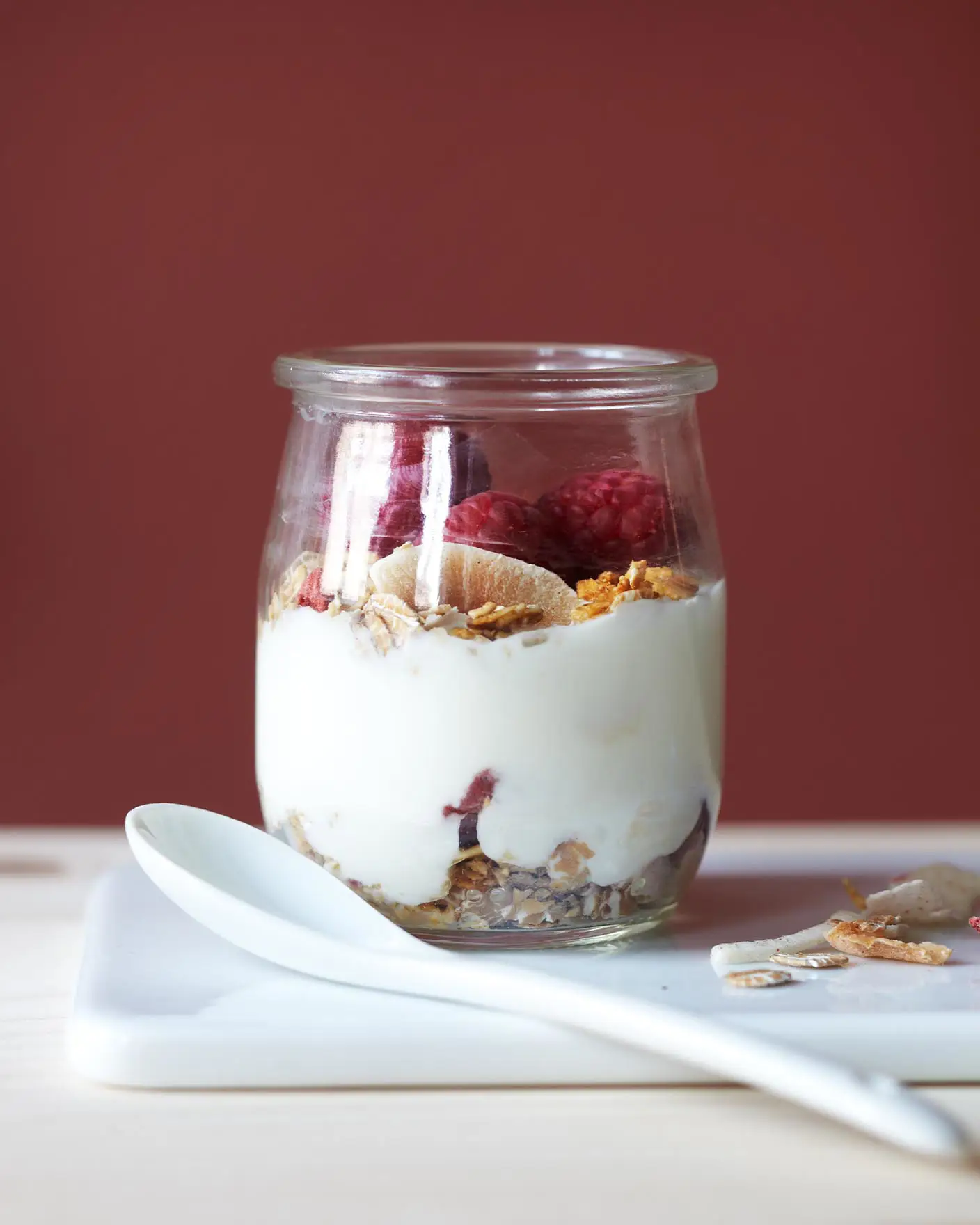 En rik rød vegg, malt i fargen 2859 Whispering Red fra Jotun, gir varme og dybde til en enkel frokost med yoghurt, granola og bær.