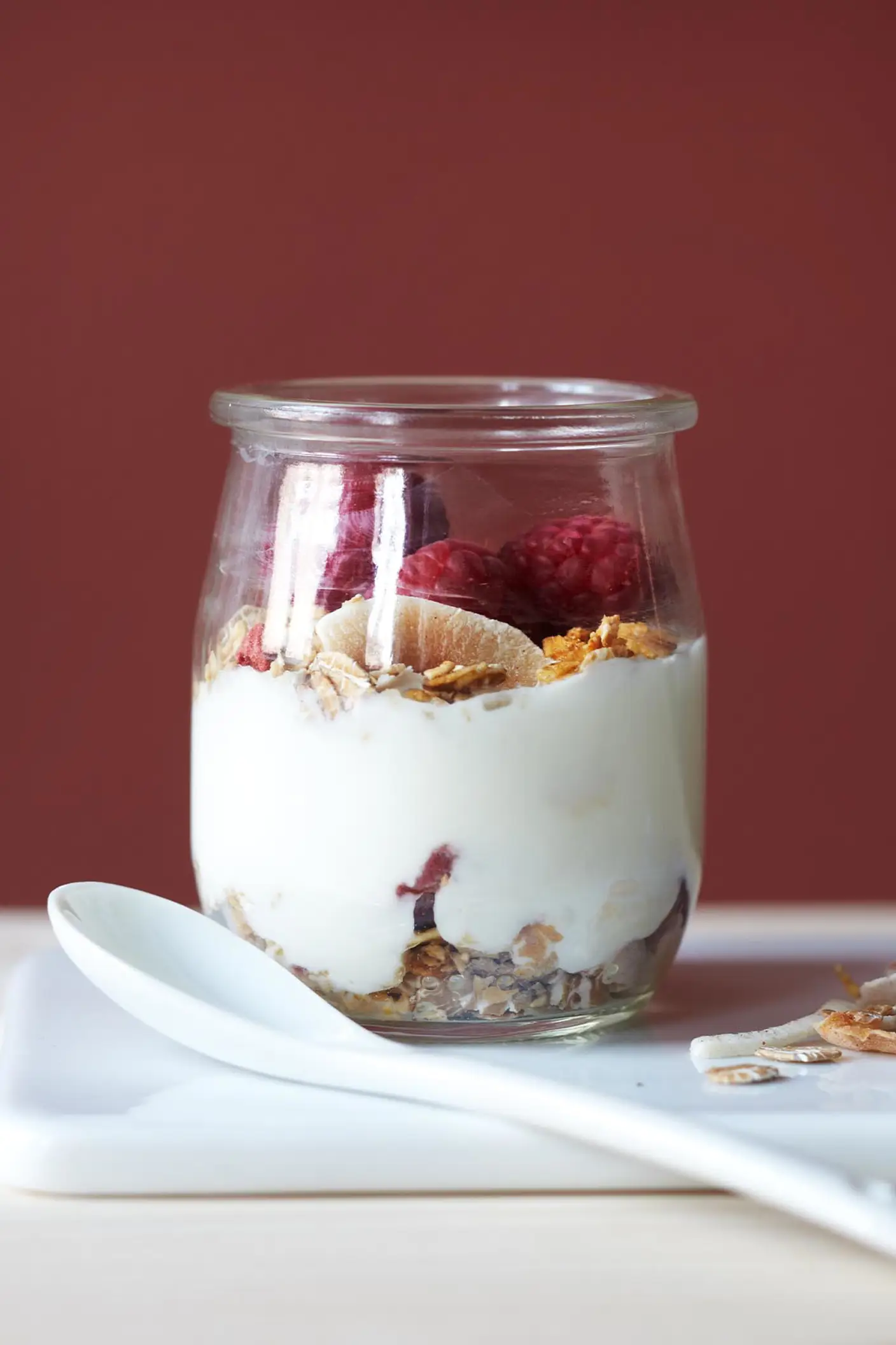 Una pared roja intensa pintada con Jotun 2859 Whispering Red aporta calidez y profundidad a un desayuno sencillo con yogur, granola y frutos rojos.