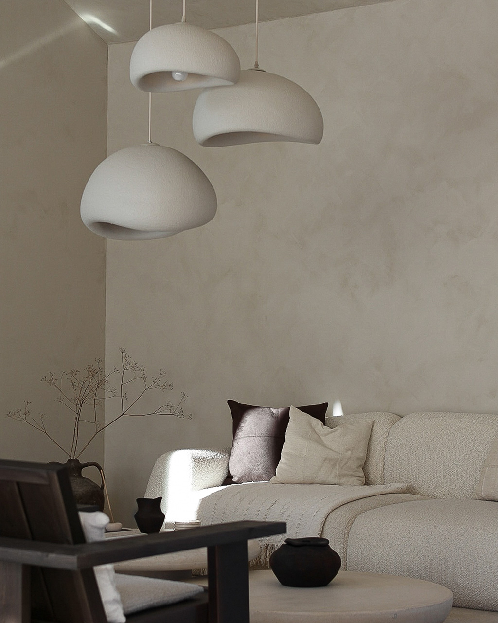 Lyst stuehjørne med beige sofa, mørke puter og organiske lamper i hvitt mot en kalkmalt vegg malt i fargen Jotun Sand