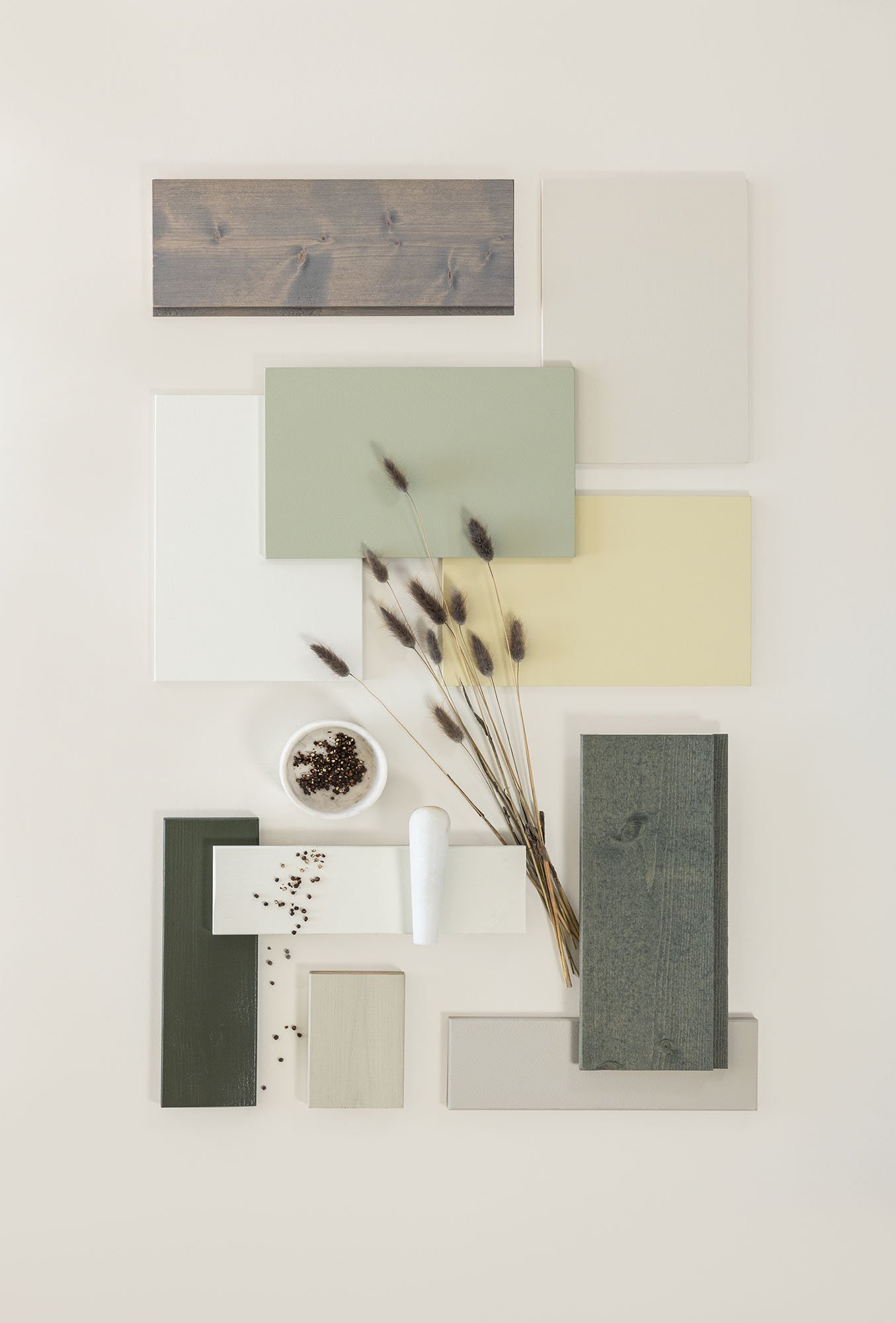 Fargeprøver i jordtoner, inkludert grønt, beige og tretekstur, arrangert med dekorative frø og tørkede stilker på en lys bakgrunn