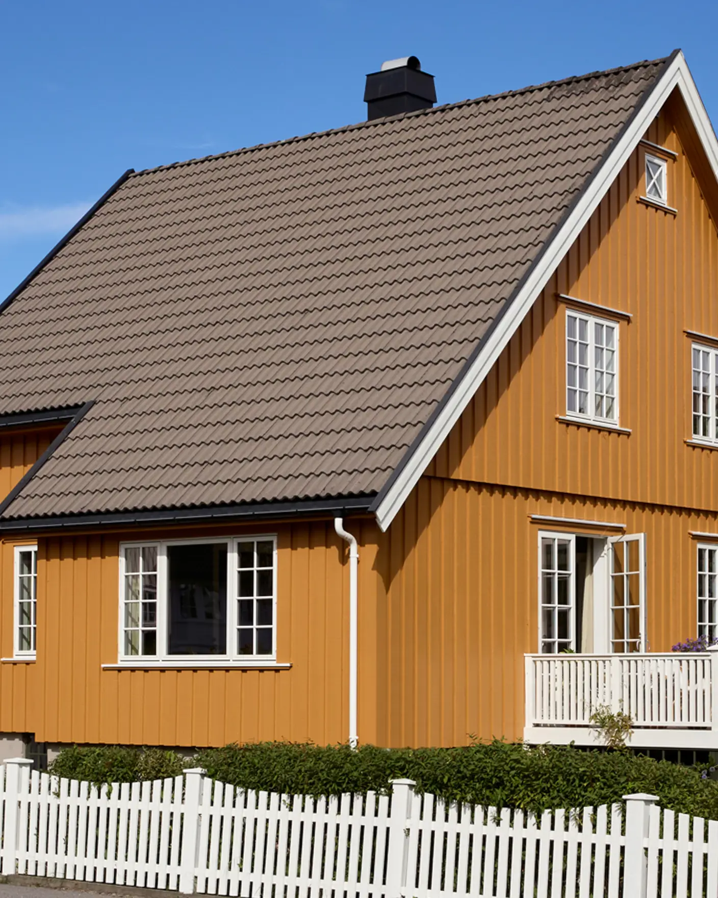 Klassisk villa med saltak, småsprossede vinduer og åpen terrassedør, fasade malt i dypt okergule JOTUN 0152 Staverngul og detaljer i hvit JOTUN 1001 Egghvit.