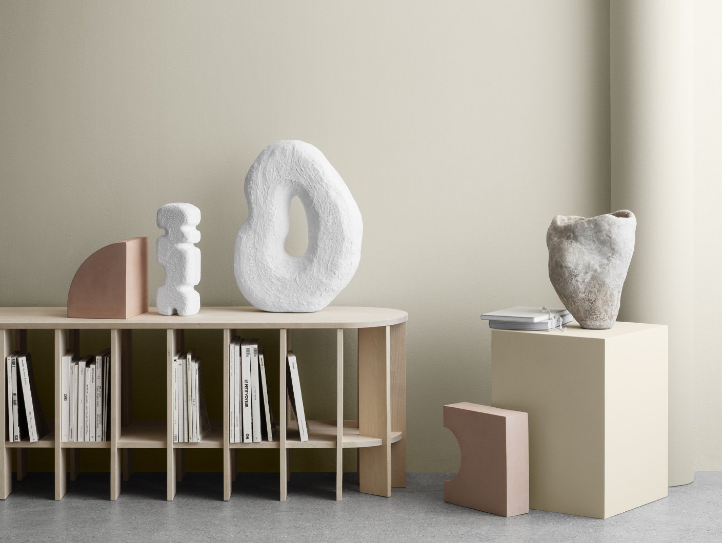 Minimalistisk interiør med skulpturelle dekorobjekter i naturmaterialer og lyse toner. Veggen er malt i en varm, beige nyanse som gir et rolig og harmonisk uttrykk, perfekt nøytral for moderne stue.