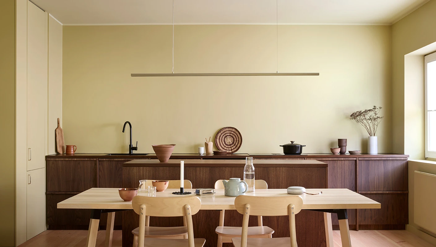 Yellow kitchen with walls painted with LADY Pure Color in the colour Earthy Yellow, light wood furniture, dark cabinets, and natural light