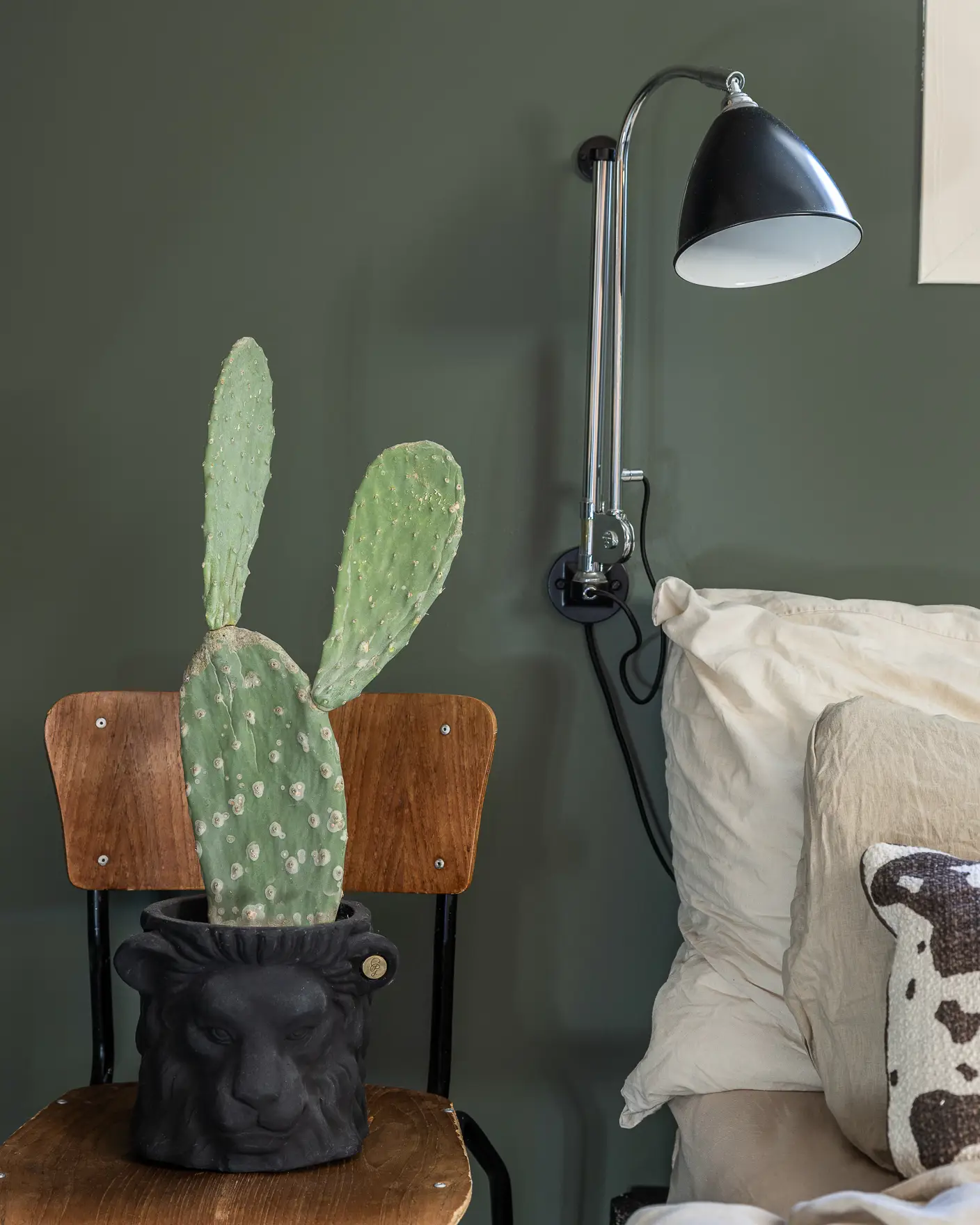 Soverom med skolestol som nattbord med en stor kaktus på, sort Bestlite lampe på grønnmalt vegg i Jotun Northern Mystic.