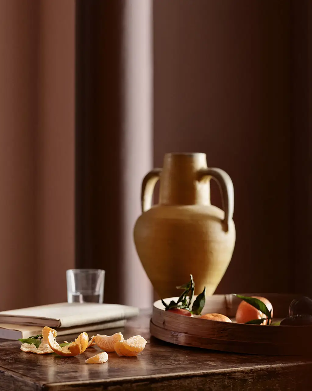 Et stilleben med sitrusfrukter og en amfora-vase mot vegger i røde Jotun 20118 Amber Red og en søyle i brunrøde Jotun 2993 Kilim