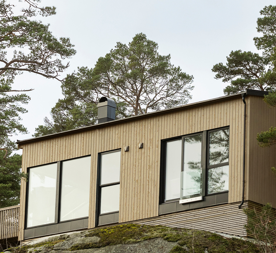 Hytte på fjell omkranset av furutrær. Kledning i tre beiset i to farger, gulbeige og sort med Jotun TREBITT Naturlig Eldet og Funkissort.