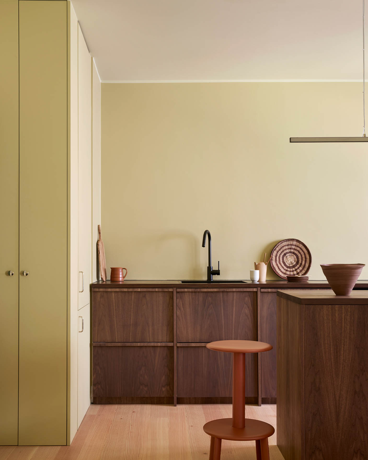 Kjøkkenveggene er malt i Jotun Earty Yellow, med skap i mørk massiv valnøtt